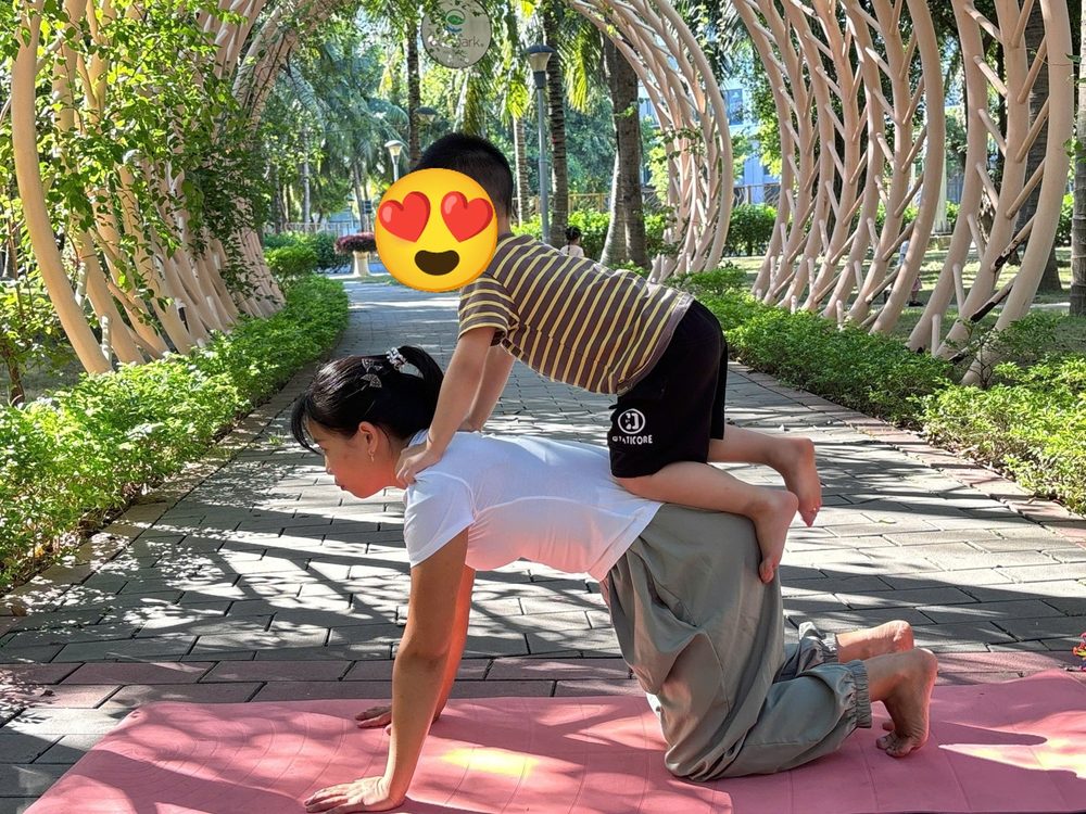 Bé ngồi trên lưng cô Sophia trong tư thế cái bàn
