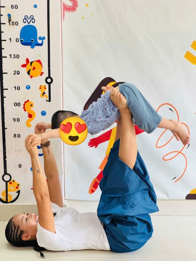 Cô Sophia nằm ngửa nâng bé bay như máy bay